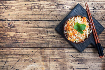 Salad of fresh grated carrots and green radish with sauce. Wooden table and dishes. Copy space