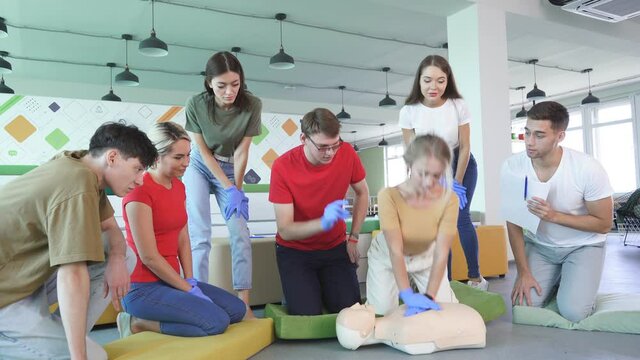 Young female learning how to make first aid heart compressions with dummies during the training indoors.