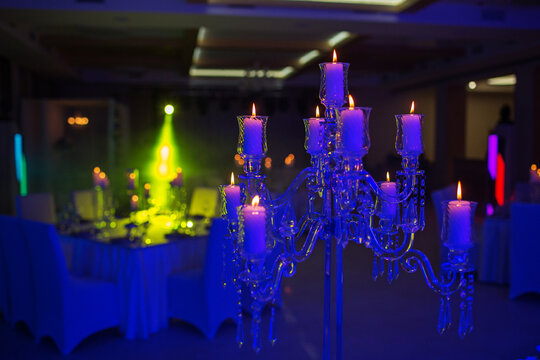festive wedding table with burning candles and crystal in blue light. Crystal candle holder as a center piece at a wedding reception.