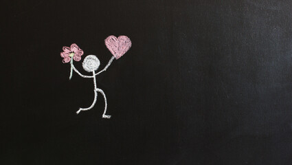 Painted man holding a pink heart and a flower. Black background. Gift concept. St. Valentina. Mother's Day. Women's Day.