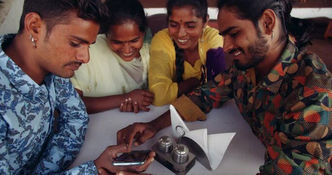Slow-motion handheld shot of friends sharing bonding smiling enjoying showing social media profile picture online on screen of a technology communication handheld device 