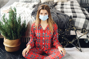 Girl wears festive pajamas and medicine mask at home