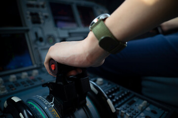 Cropped hands of pilot flying a commercial airplane, cockpit view close up of hands. Captain hand...
