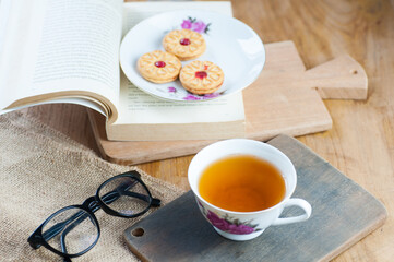 a cup of tea with a book and cake as decor