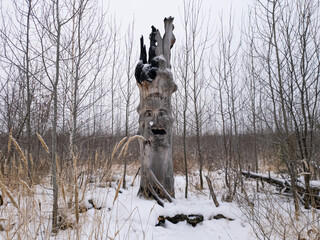 A lonely idol carved from an old tree in the middle of a winter forest