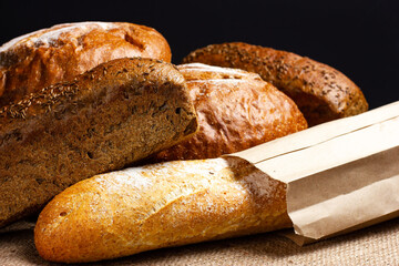 White French baguette and black rustic bread on a burlap background. Bakery products, Provence rustic style.
