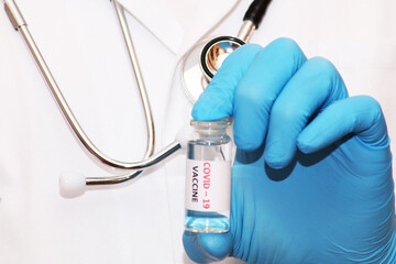 Fototapeta premium Covid-19 corona virus fight concept. The doctor is ready to vaccinate against coronavirus, holds a syringe and vaccine in his hands. Concept: disease, medical care, science.