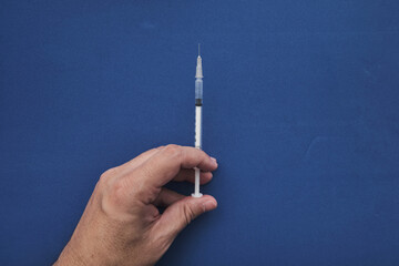 Doctor hand holding syringe to vaccinate with blue background and copy space
