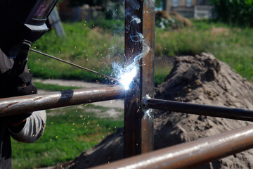 Fototapeta na wymiar male welder welds iron parts at construction