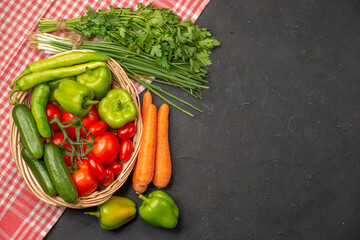 Half shot of fresh various organic vegetables in a wooden basket on orange stripped towel on dark background
