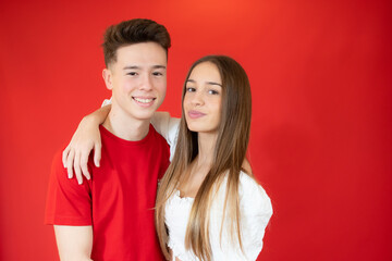 Young couple embracing each other over red background.