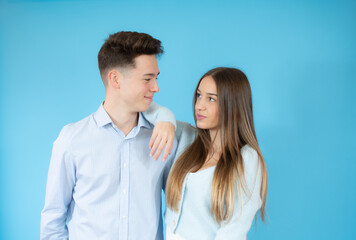 A young boy and a girl looking each other in love over blue background.
