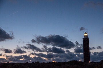 Lighthouse standing on the Dutch coast with a dramatic. and colorful dusk or dawn sky behind it. High quality photo