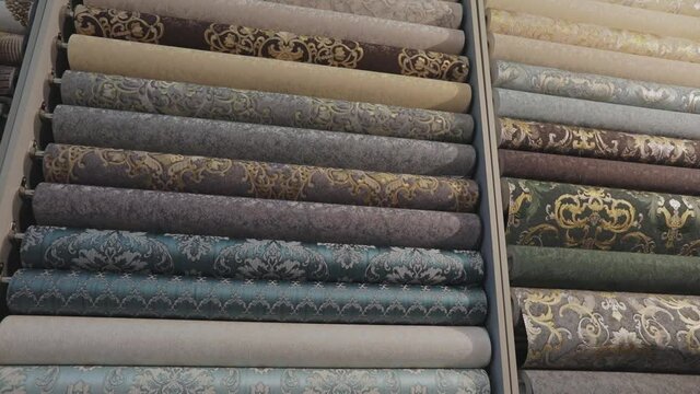 Wallpaper with patterns. Stands with rolls of wallpaper samples in the store. Stands with new samples. Rolls with wallpaper. Closeup