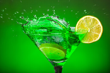 Green drink in a glass. Green water or limnad. A splash of green liquid similar to absinthe. Alcohol and alcoholism.