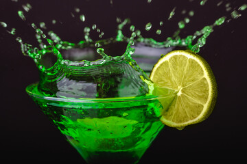 Green drink in a glass. Green water or limnad. A splash of green liquid similar to absinthe. Alcohol and alcoholism.