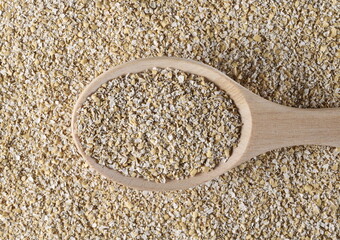 Oat bran pile with wooden spoon background and texture