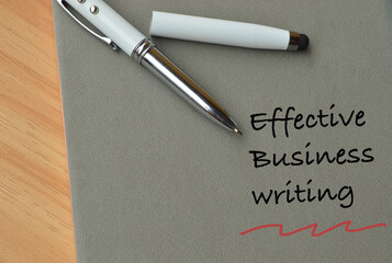 Top view of pen and notebook written with text EFFECTIVE BUSINESS WRITING.