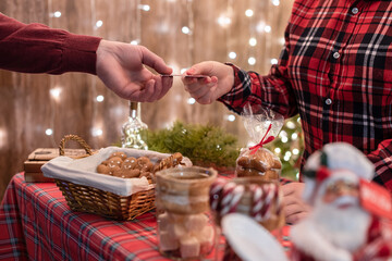 Man customer buying christmas sweets, gingerbread at the bakery giving credit card to the woman seller