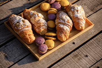 Picnic at the park. colored french macaroons or macarons and croissants on wooden tray on a hot summer day. Picnic lunch. selective focus