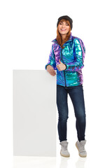 Fototapeta premium Happy Young Woman In Winter Clothes Is Posing With White Banner And Showing Thumb Up