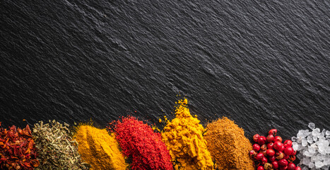 Bright and colorful spices on the black stone background. Different spices and herbs for background.