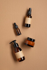Set of amber glass cosmetic bottles on brown background. Natural cosmetics packaging design. Flat...