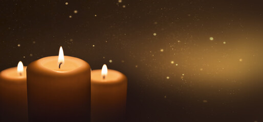 Several burning candles with festive bokeh on a dark gold background. Banner with a copy of the space.