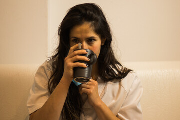 Mujer enfermera descansando en un sofá bebiendo de una taza