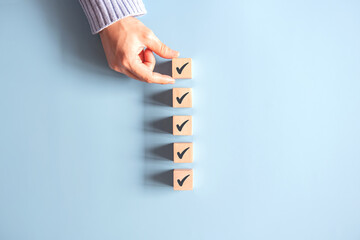 Wood cube with check mark on blue background, Checklist concept, Copy space.