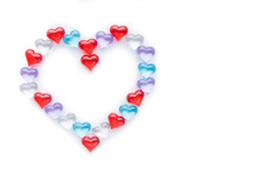Small multicolored hearts lie in the shape of a large heart on a white background. Layout for Valentine's Day. Isolate. View from above. Copyspace