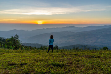 Fototapeta premium Young woman traveler looking at the sunrise over the mountain