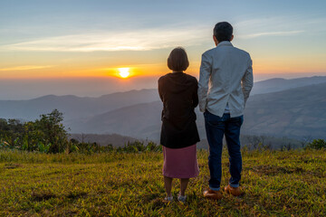 Young couple traveler looking at the sunrise over the mountain