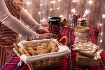 Christmas pastry shop. Woman seller, waitress selling hot chocolate in paper cup, gingerbread, marshmallows, cookies, sweets in a small cozy cafe.