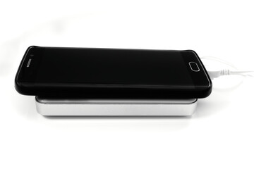 Black mobile phone charging with an external white battery, on a white background. Connection by cable.
