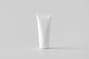 White plastic cream tube mockup on a grey background.