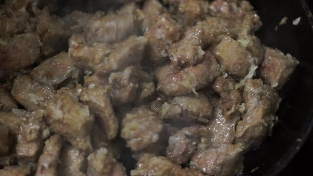 Pieces of beef liver are stewed with onions in frying pan