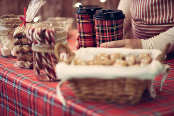 Christmas pastry shop. Woman seller, waitress selling hot chocolate in paper cup, gingerbread, marshmallows, cookies, sweets in a small cozy cafe. Cropped