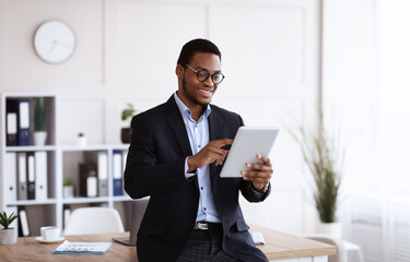 Happy african american young businessman using digital tablet in office