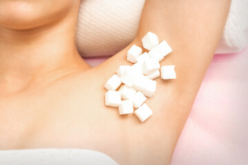 Sugaring concept. White sugar cubes lying on the armpit of a young female