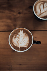 cup of hot latte art coffee on wooden table