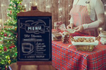 Christmas pastry shop. Woman seller, waitress counting money selling gingerbread, marshmallows,...