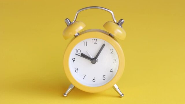 Yellow alarm clock on yellow background close-up