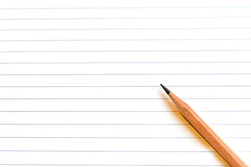 Top view of pencil on a blank empty lined sheet paper of notebook with copy space