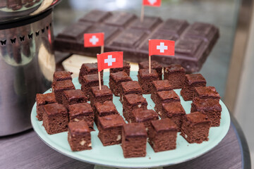 Chocolate and cocoa brownie cakes and chocolate bar on plate and mini Switzerland flag plant on...