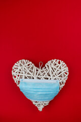White heart with a blue face mask on a red background. Concept of a Valentine´s day during Coronavirus or Covid pandemic.