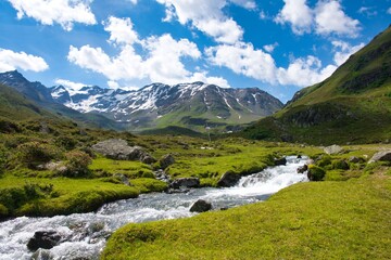 mountain panorama with raging river through the green fields. Autumn winter landscape from Davos Dischma Switzerland. Mountain peak with snow