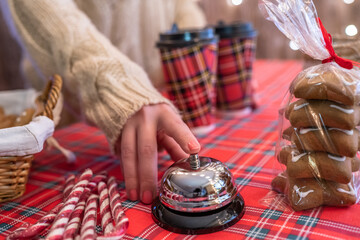 Christmas pastry shop. Woman seller, waitress ringing bell to warn that coffee in paper cup is ready. Gingerbread cookies, marshmallows in a small cozy cafe.