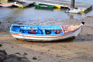 Fototapeta na wymiar Old Colourful Wooden Fishing Boat on Sandy Beach 