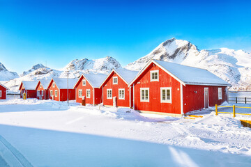 Fototapeta na wymiar Astonishing winter scenery with traditional Norwegian red wooden houses on the shore of Sundstraumen strait